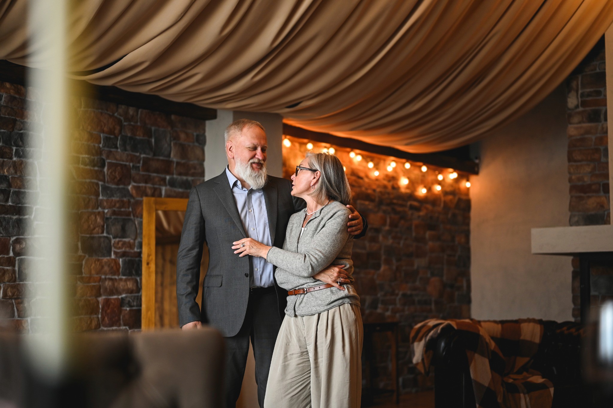 A mature couple smiling together in a warm room